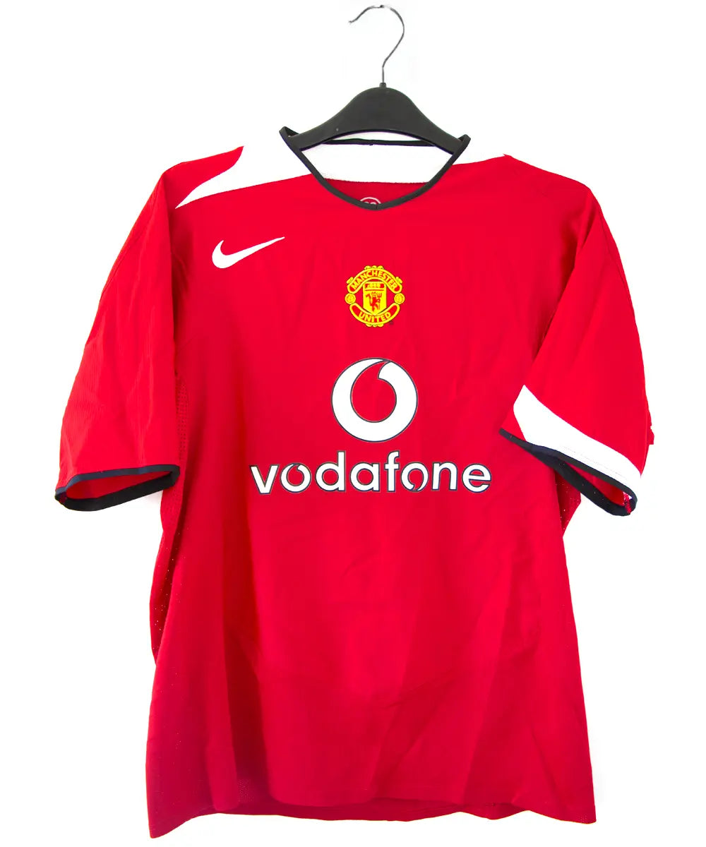 Maillot domicile de manchester united rouge, blanc et noir, édité lors de la saison 2004-2005 et la saison 2005-2006. On peut retrouver l'équipementier nike et le sponsor vodafone.