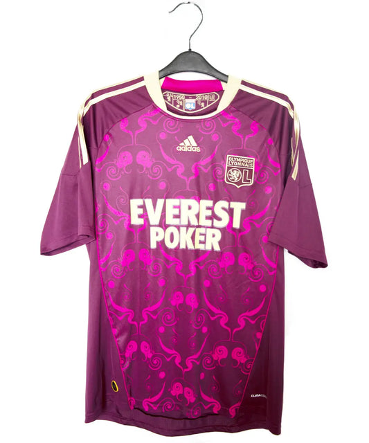 Maillot extérieur de l'ol de la saison 2010-2011. Le maillot est de couleur violet et dorée. On peut retrouver l'équipementier adidas et le sponsor everest poker