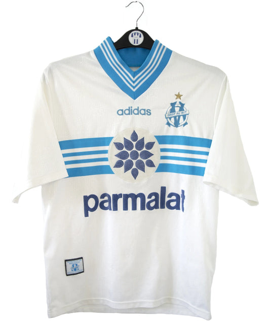 Maillot de foot vintage domicile blanc et bleu de l'om de la saison 1996/1997. On peut retrouver l'équipementier adidas et le sponsor Parmalat. Il s'agit d'un maillot authentique