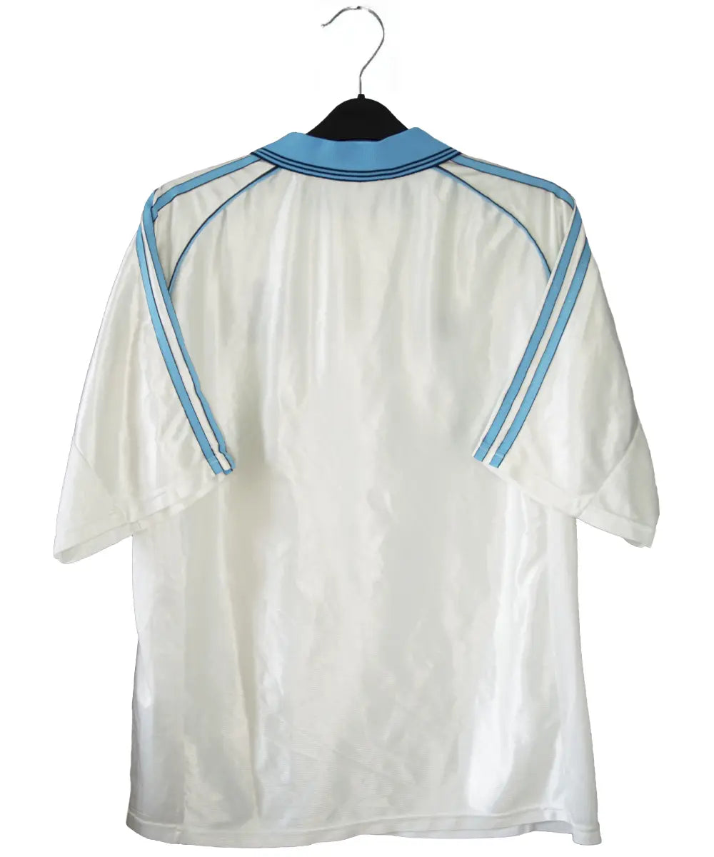 Maillot domicile de l'om de la saison 1998-1999. Le maillot est de couleur blanc et bleu. On peut retrouver l'équipementier adidas et le sponsor ericsson