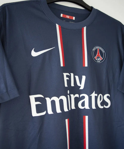 Maillot domicile du PSG bleu blanc et rouge, de la saison 2012-2013. On peut retrouver l'équipementier nike et le sponsor fly emirates. Sur cette photo on peut voir le maillot de côté