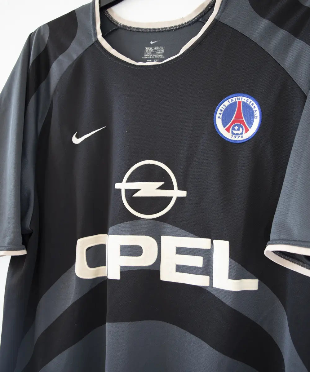 Maillot third du PSG de la saison 2001-2002. Le maillot est de couleur noir et gris. On peut retrouver le sponsor Opel ainsi que l'équipementier Nike.