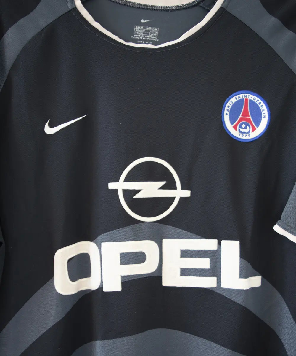 Maillot third du PSG de la saison 2001-2002. Le maillot est de couleur noir et gris. On peut retrouver le sponsor Opel ainsi que l'équipementier Nike.