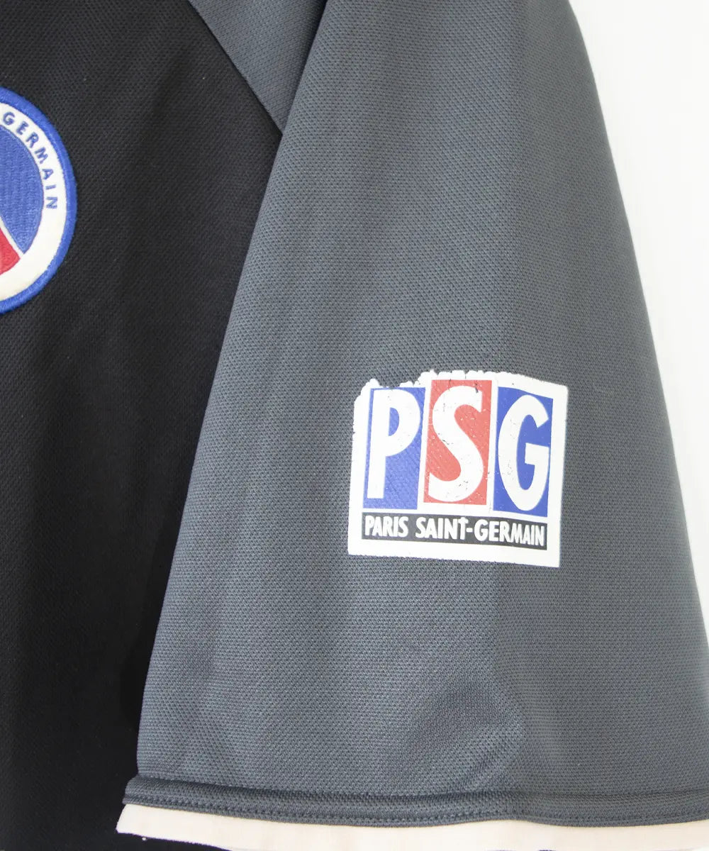 Maillot third du PSG de la saison 2001-2002. Le maillot est de couleur noir et gris. On peut retrouver le sponsor Opel ainsi que l'équipementier Nike.