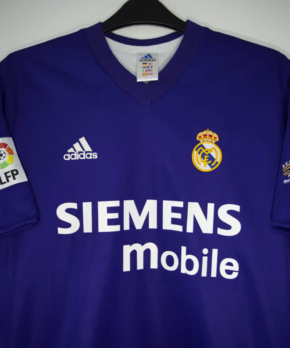 Maillot vintage violet et blanc third du real madrid de la saison 2002-2003. On peut retrouver l'équipementier adidas et le sponsor siemens mobile. Il s'agit du maillot du centenaire. Le maillot est floqué du numéro 5 Zinedine Zidane