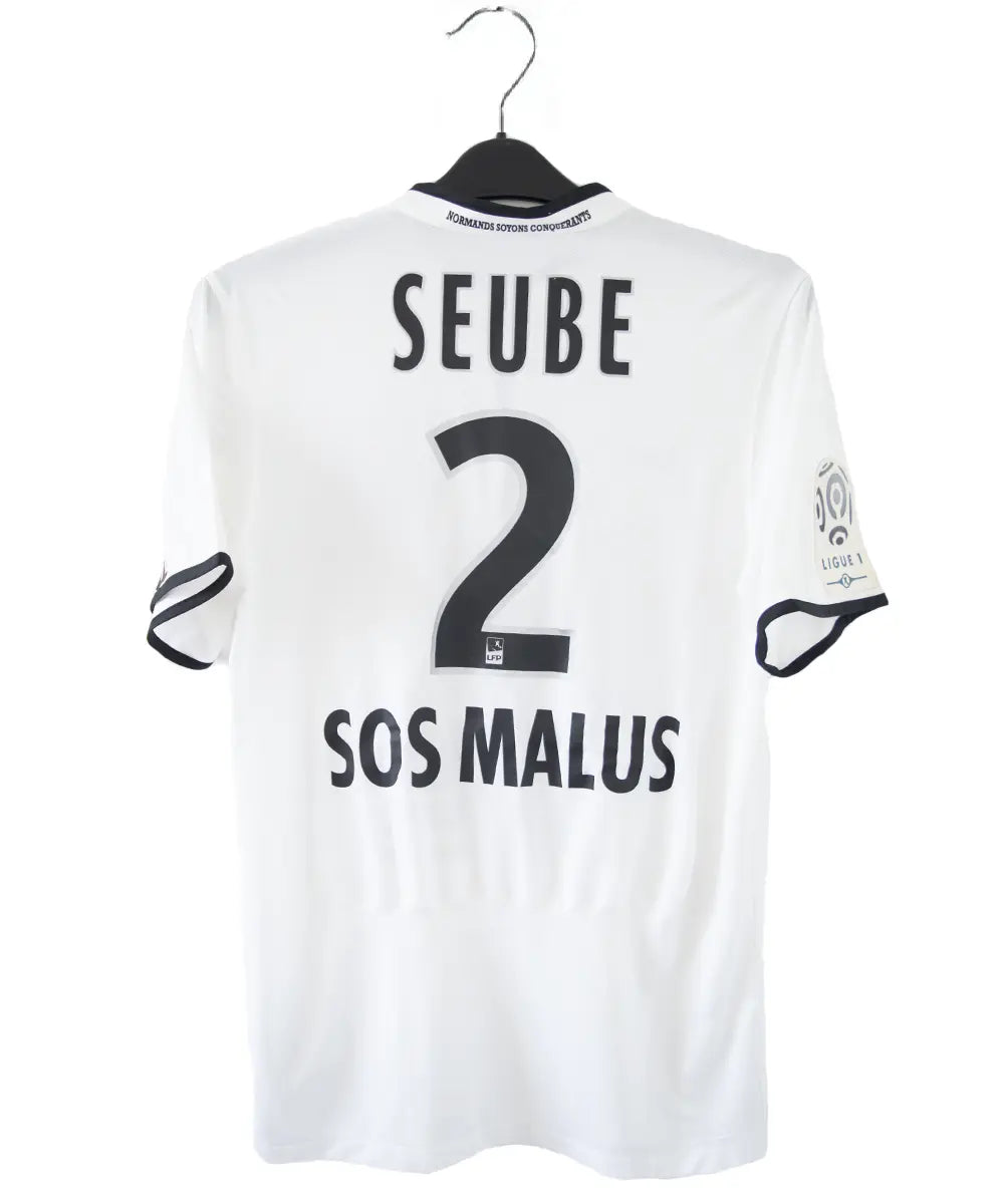 Maillot third du SM Caen de la saison 2014-2015 de couleur blanc et noir. On peut retrouver l'équipementier nike, le sponsor GDE et le sponsor SAS Malus. Le maillot est floqué du numéro 2 Nicolas Seube. Le maillot est aussi signé par Seube