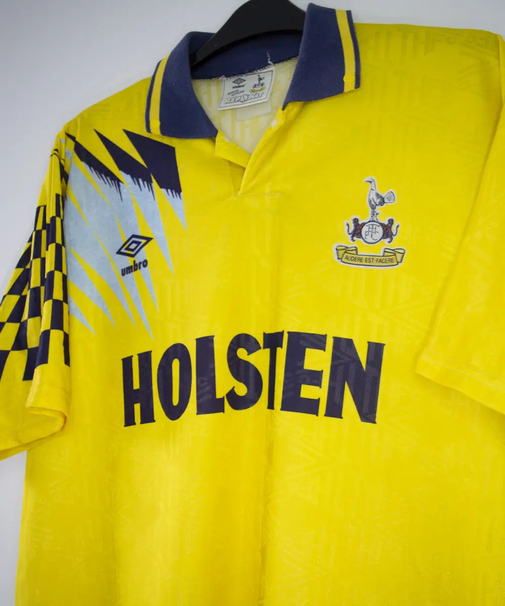 Maillot extérieur de Tottenham de la saison 1991-1995 de couleur jaune. On peut retrouver l'équipementier Umbro et le sponsor Holsten