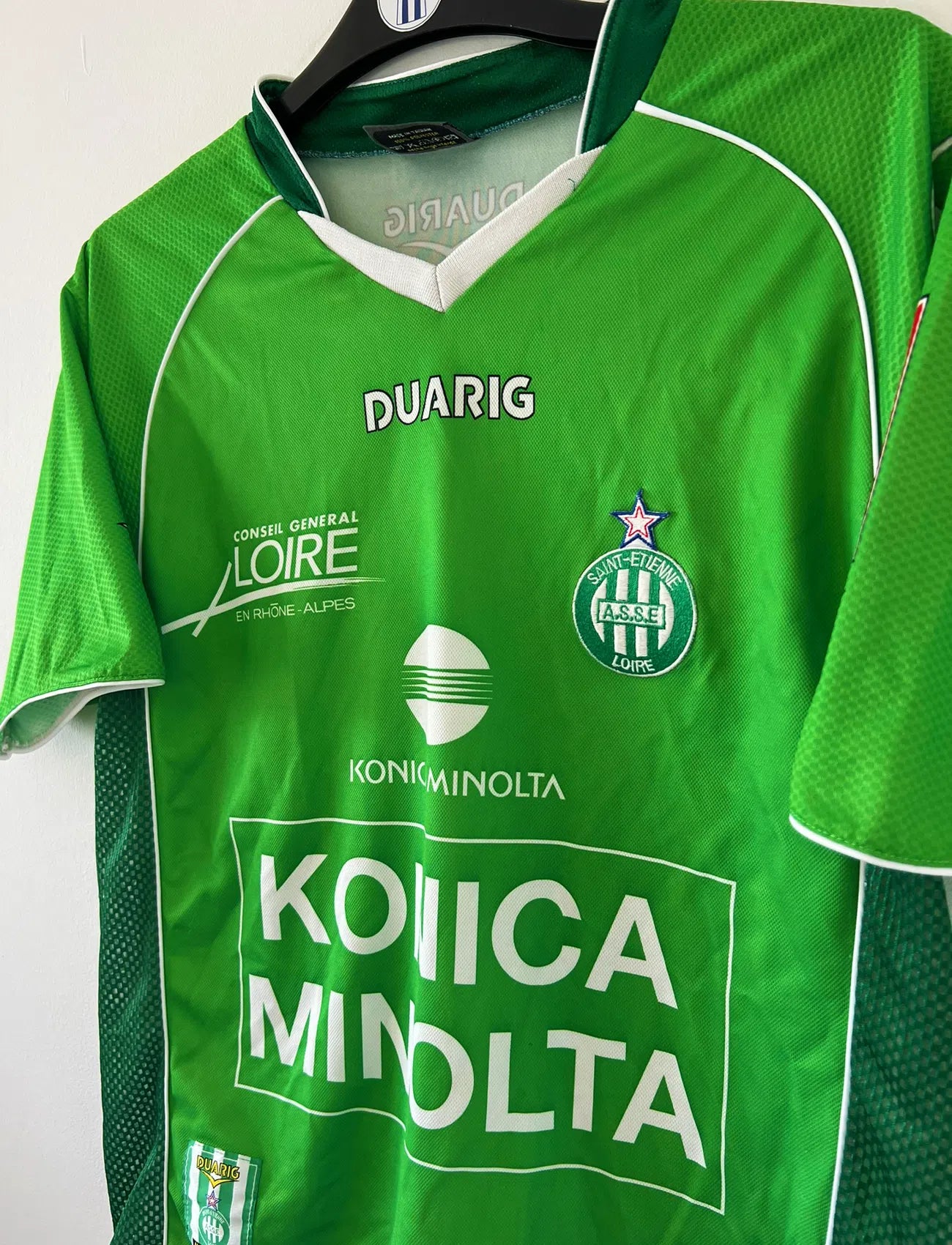 Maillot de foot vintage domicile de l'ASSE de la saison 2004-2005. Le maillot est de couleur vert et blanc. On peut retrouver l'équipementier duarig et le sponsor Konica Minolta. Il s'agit d'un maillot authentique