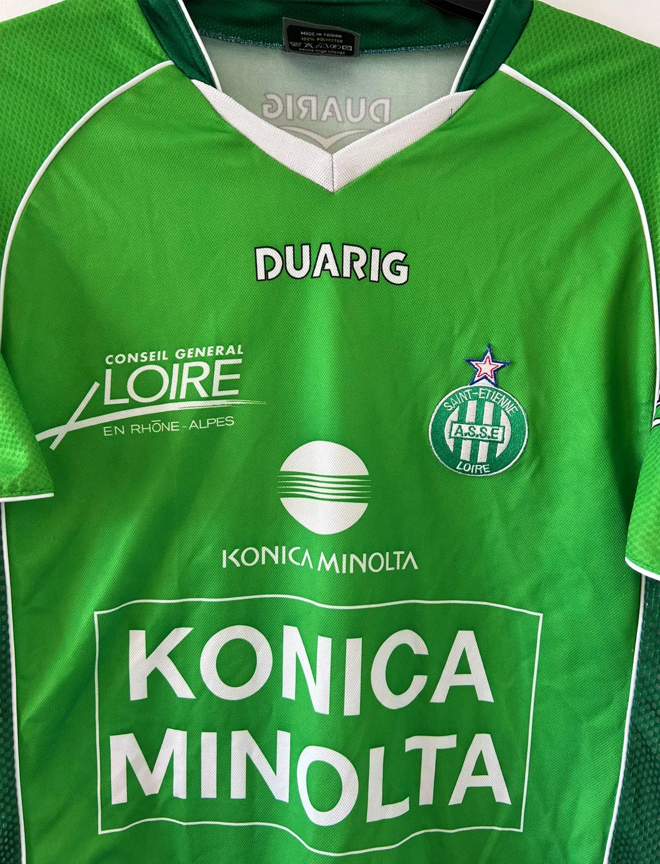 Maillot de foot vintage domicile de l'ASSE de la saison 2004-2005. Le maillot est de couleur vert et blanc. On peut retrouver l'équipementier duarig et le sponsor Konica Minolta. Il s'agit d'un maillot authentique