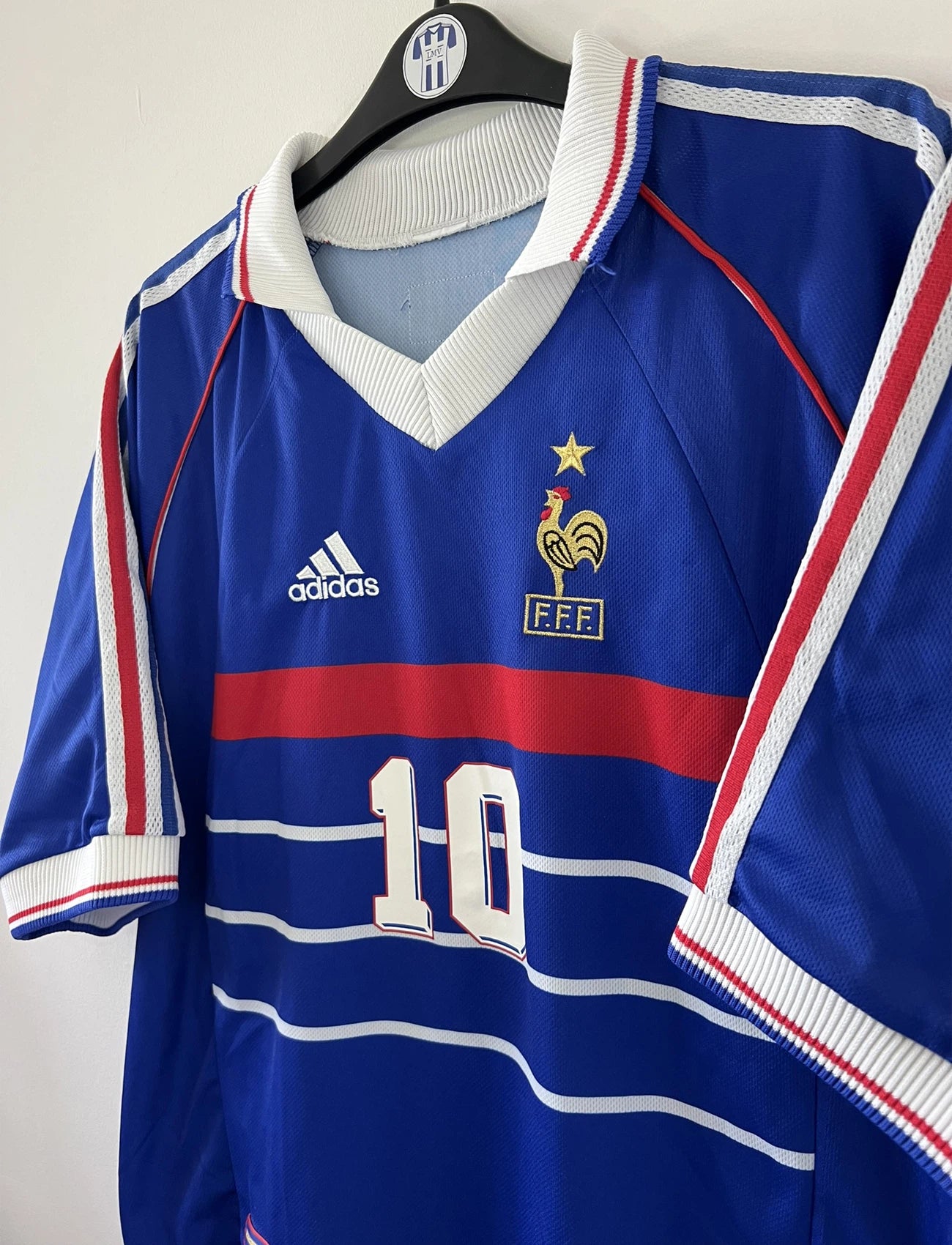 Maillot de foot vintage domicile de l'équipe de france 1998. On peut retrouver l'équipementier adidas. Le maillot est de couleur bleu blanc et rouge. Le maillot est floqué du numéro 10 Zinedine Zidane. Il s'agit d'un maillot authentique d'époque.
