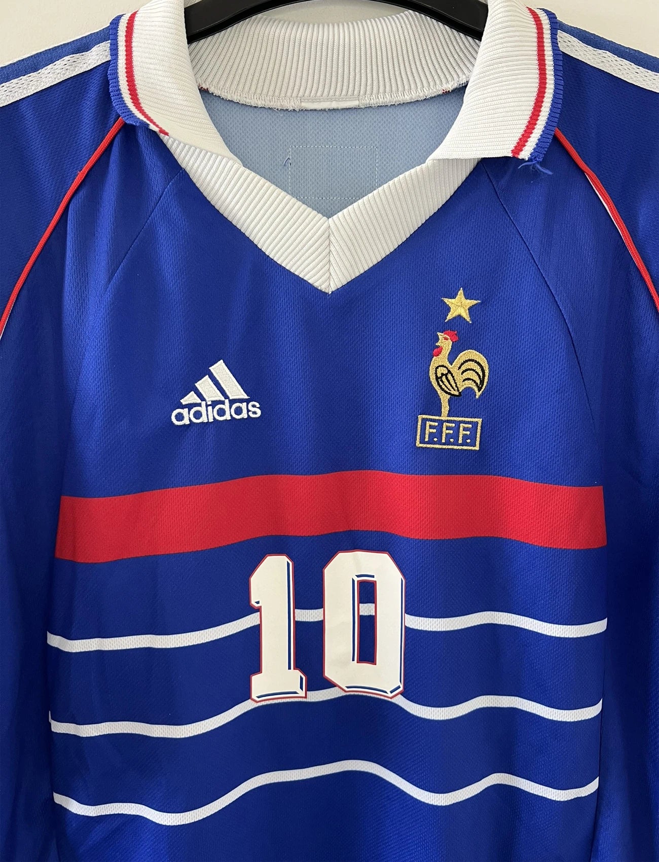 Maillot de foot vintage domicile de l'équipe de france 1998. On peut retrouver l'équipementier adidas. Le maillot est de couleur bleu blanc et rouge. Le maillot est floqué du numéro 10 Zinedine Zidane. Il s'agit d'un maillot authentique d'époque.