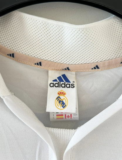 Maillot de foot vintage domicile blanc du Real Madrid 2001/2002. On peeut retrouver l'équipementier Adidas et le sponsor Real Madrid.com. Le maillot est floqué du numéro 5 Zinedine Zidane. Il s'agit d'un maillot authentique d'époque.