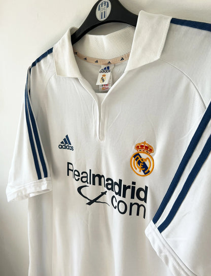 Maillot de foot vintage domicile blanc du Real Madrid 2001/2002. On peeut retrouver l'équipementier Adidas et le sponsor Real Madrid.com. Le maillot est floqué du numéro 5 Zinedine Zidane. Il s'agit d'un maillot authentique d'époque.