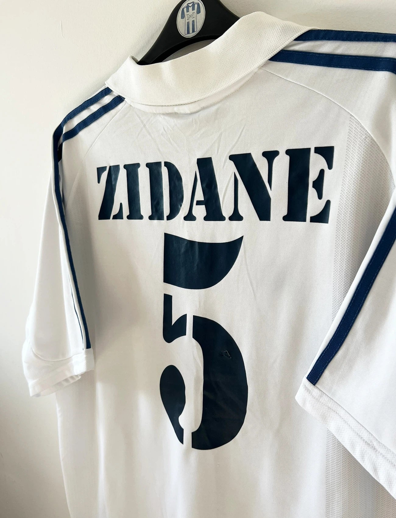 Maillot de foot vintage domicile blanc du Real Madrid 2001/2002. On peeut retrouver l'équipementier Adidas et le sponsor Real Madrid.com. Le maillot est floqué du numéro 5 Zinedine Zidane. Il s'agit d'un maillot authentique d'époque.