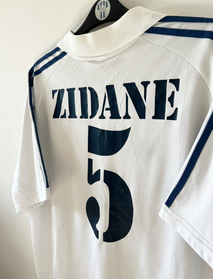 Maillot de foot vintage domicile blanc du Real Madrid 2001/2002. On peeut retrouver l'équipementier Adidas et le sponsor Real Madrid.com. Le maillot est floqué du numéro 5 Zinedine Zidane. Il s'agit d'un maillot authentique d'époque.