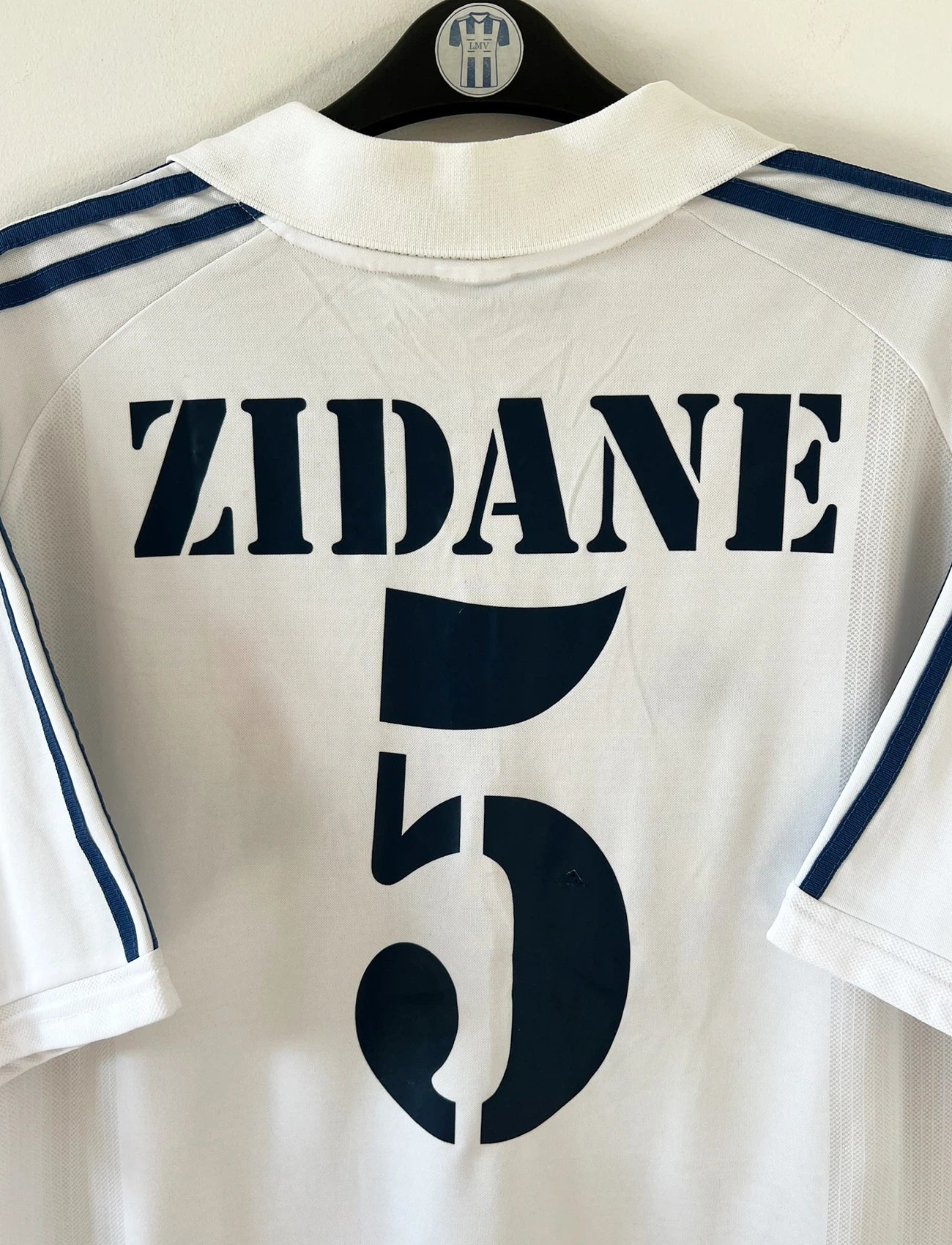Maillot de foot vintage domicile blanc du Real Madrid 2001/2002. On peeut retrouver l'équipementier Adidas et le sponsor Real Madrid.com. Le maillot est floqué du numéro 5 Zinedine Zidane. Il s'agit d'un maillot authentique d'époque.
