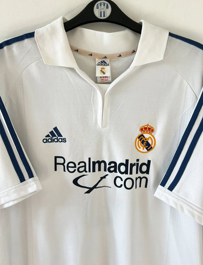 Maillot de foot vintage domicile blanc du Real Madrid 2001/2002. On peeut retrouver l'équipementier Adidas et le sponsor Real Madrid.com. Le maillot est floqué du numéro 5 Zinedine Zidane. Il s'agit d'un maillot authentique d'époque.