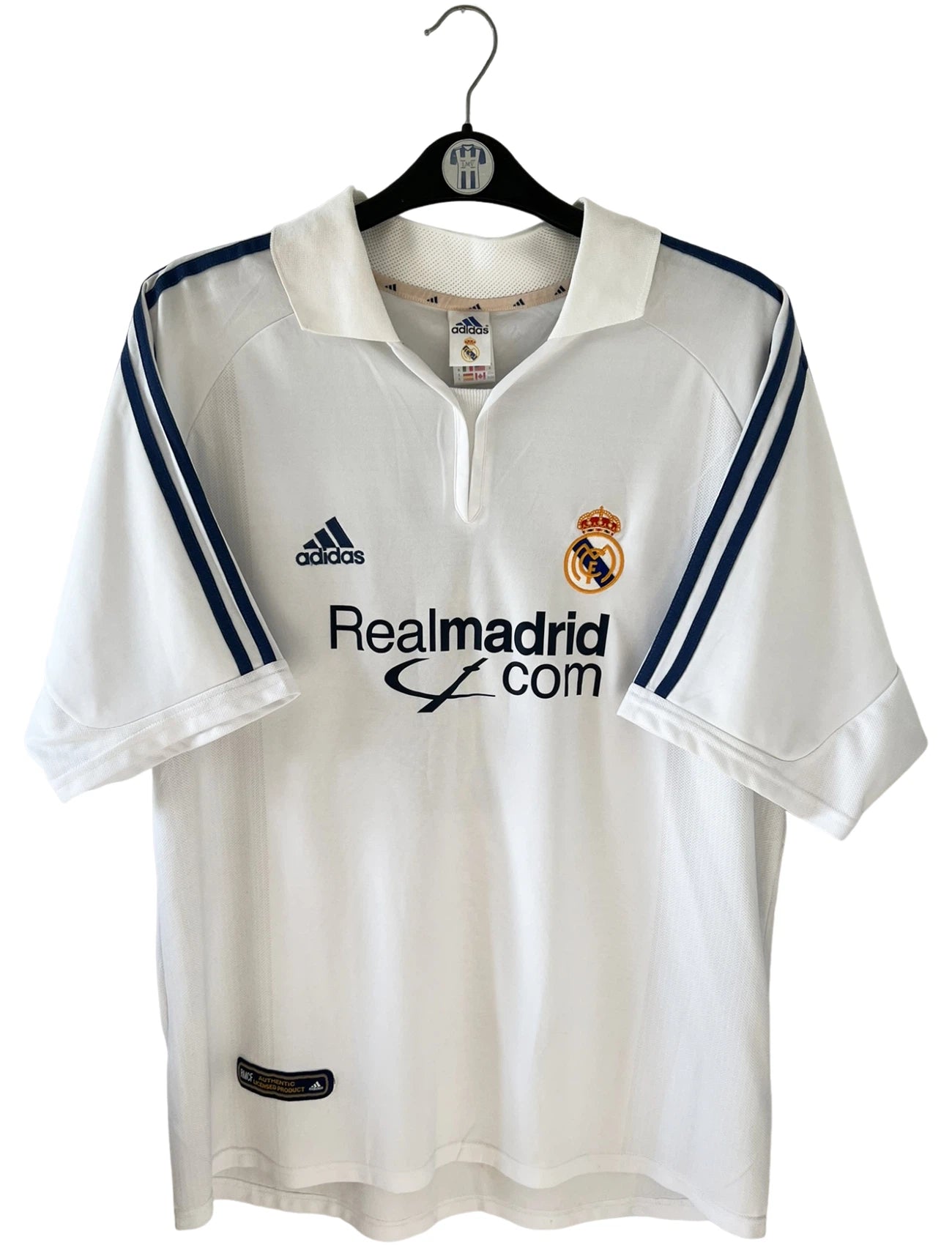 Maillot de foot vintage domicile blanc du Real Madrid 2001/2002. On peeut retrouver l'équipementier Adidas et le sponsor Real Madrid.com. Le maillot est floqué du numéro 5 Zinedine Zidane. Il s'agit d'un maillot authentique d'époque.