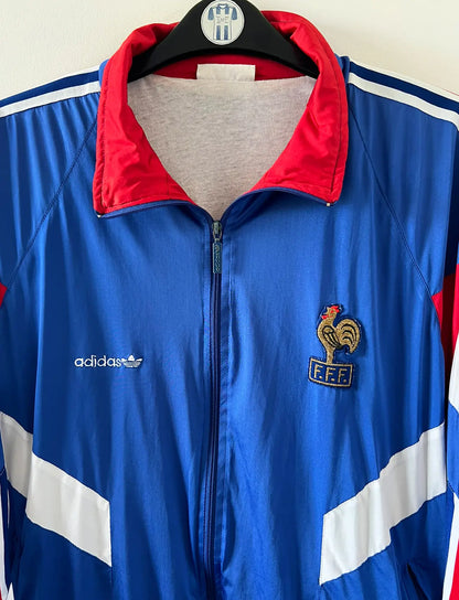Veste foot vintage bleue de l'Equipe de France 1992. On peut retrouver l'équipementier Adidas. Il s'agit d'une veste authentique d'époque.