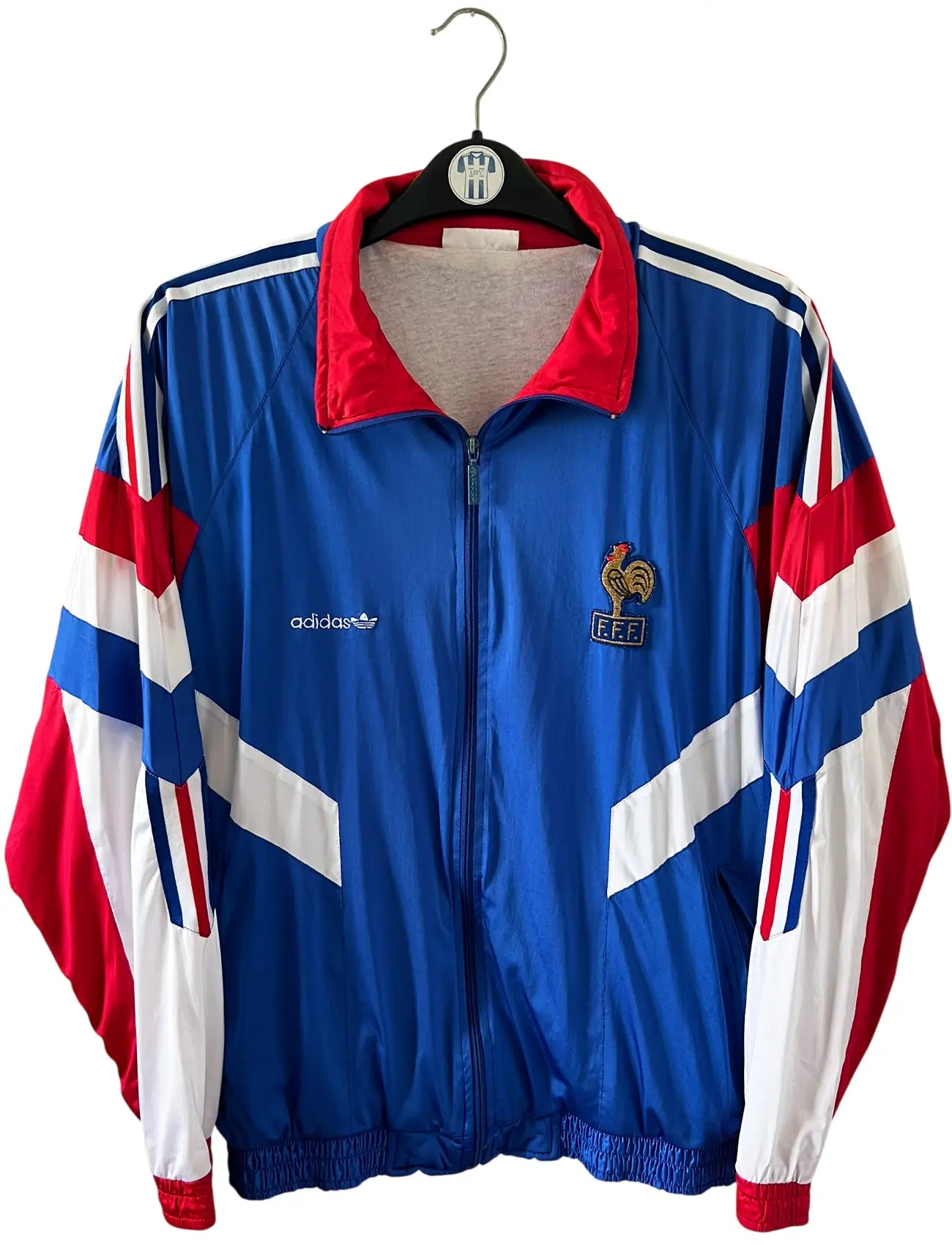 Veste foot vintage bleue de l'Equipe de France 1992. On peut retrouver l'équipementier Adidas. Il s'agit d'une veste authentique d'époque.