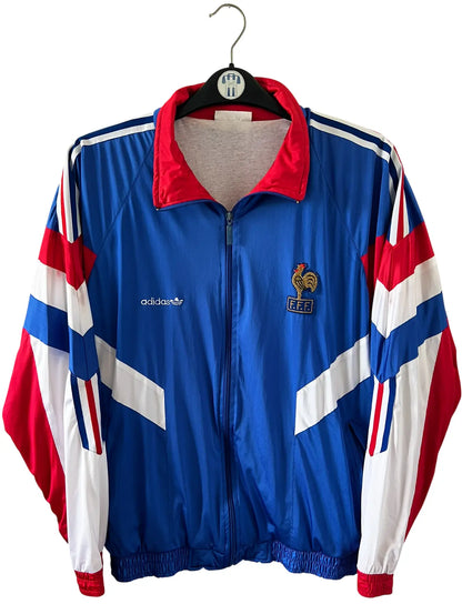 Veste foot vintage bleue de l'Equipe de France 1992. On peut retrouver l'équipementier Adidas. Il s'agit d'une veste authentique d'époque.
