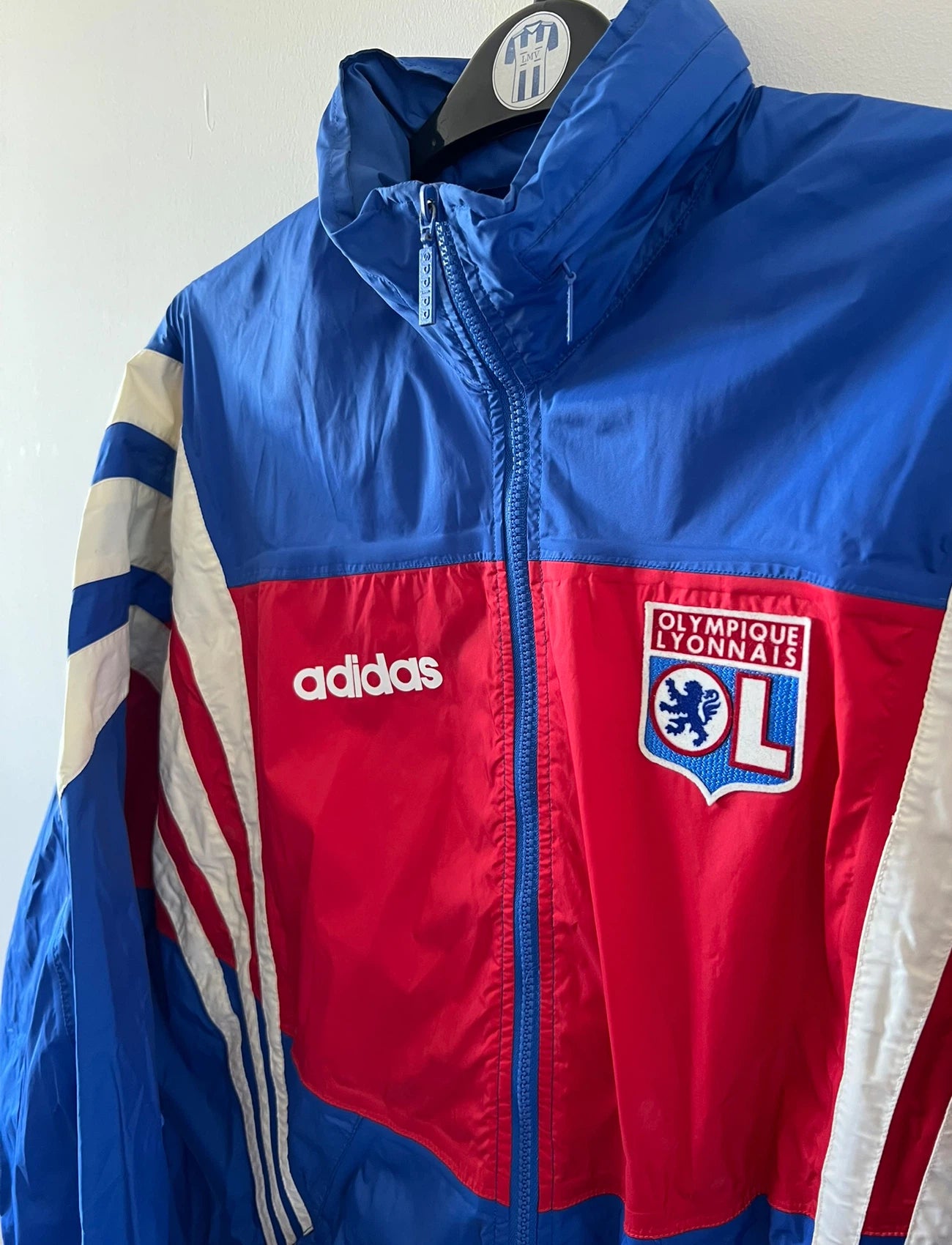 Veste de foot vintage bleu de l'OL 1996. On peut retrouver l'équipementier Adidas. Il s'agit d'une veste authentique d'époque.
