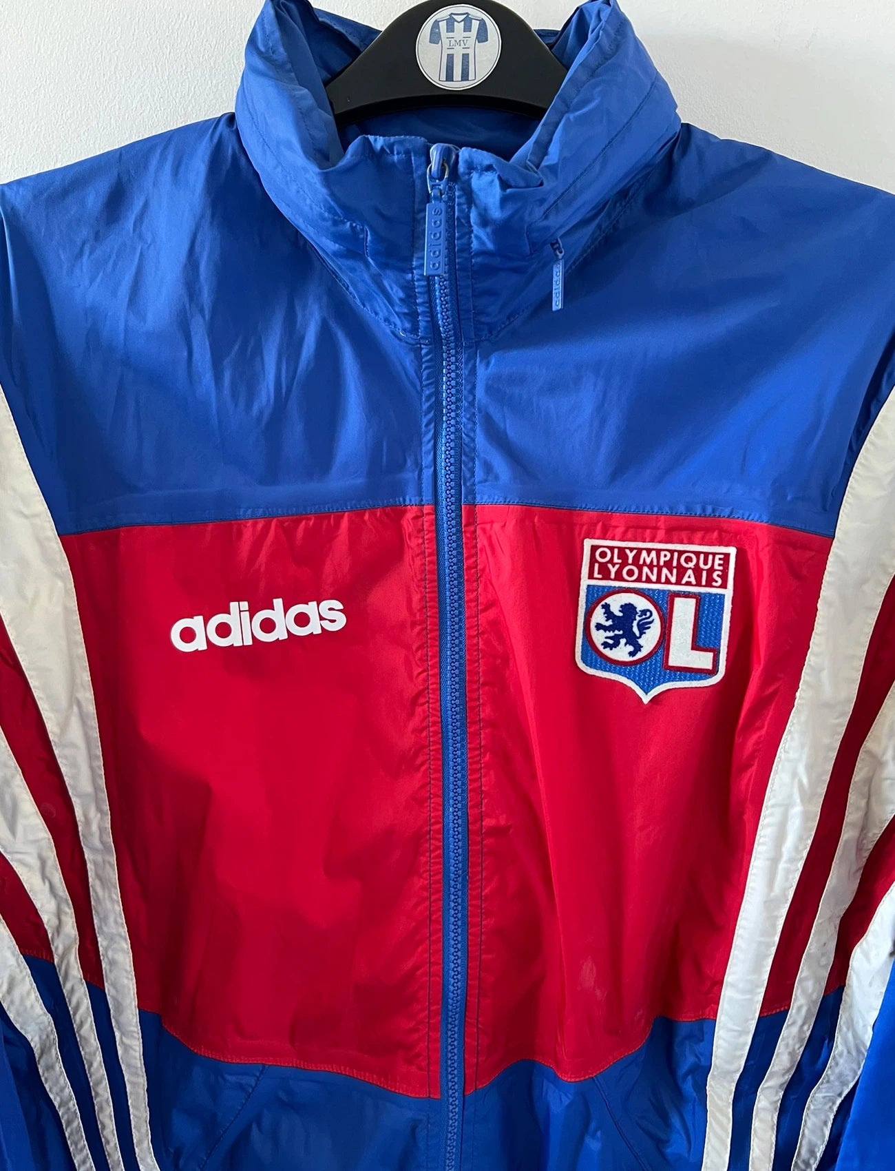 Veste de foot vintage bleu de l'OL 1996. On peut retrouver l'équipementier Adidas. Il s'agit d'une veste authentique d'époque.