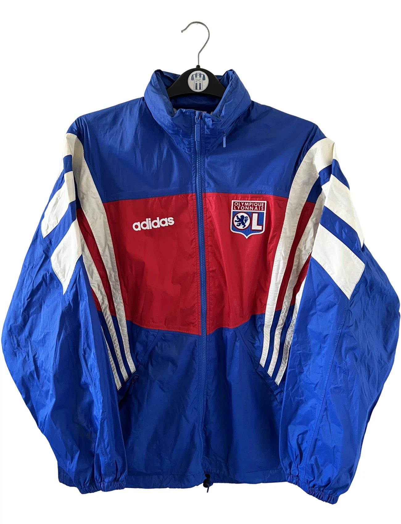 Veste de foot vintage bleu de l'OL 1996. On peut retrouver l'équipementier Adidas. Il s'agit d'une veste authentique d'époque.