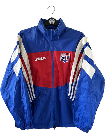 Veste de foot vintage bleu de l'OL 1996. On peut retrouver l'équipementier Adidas. Il s'agit d'une veste authentique d'époque.