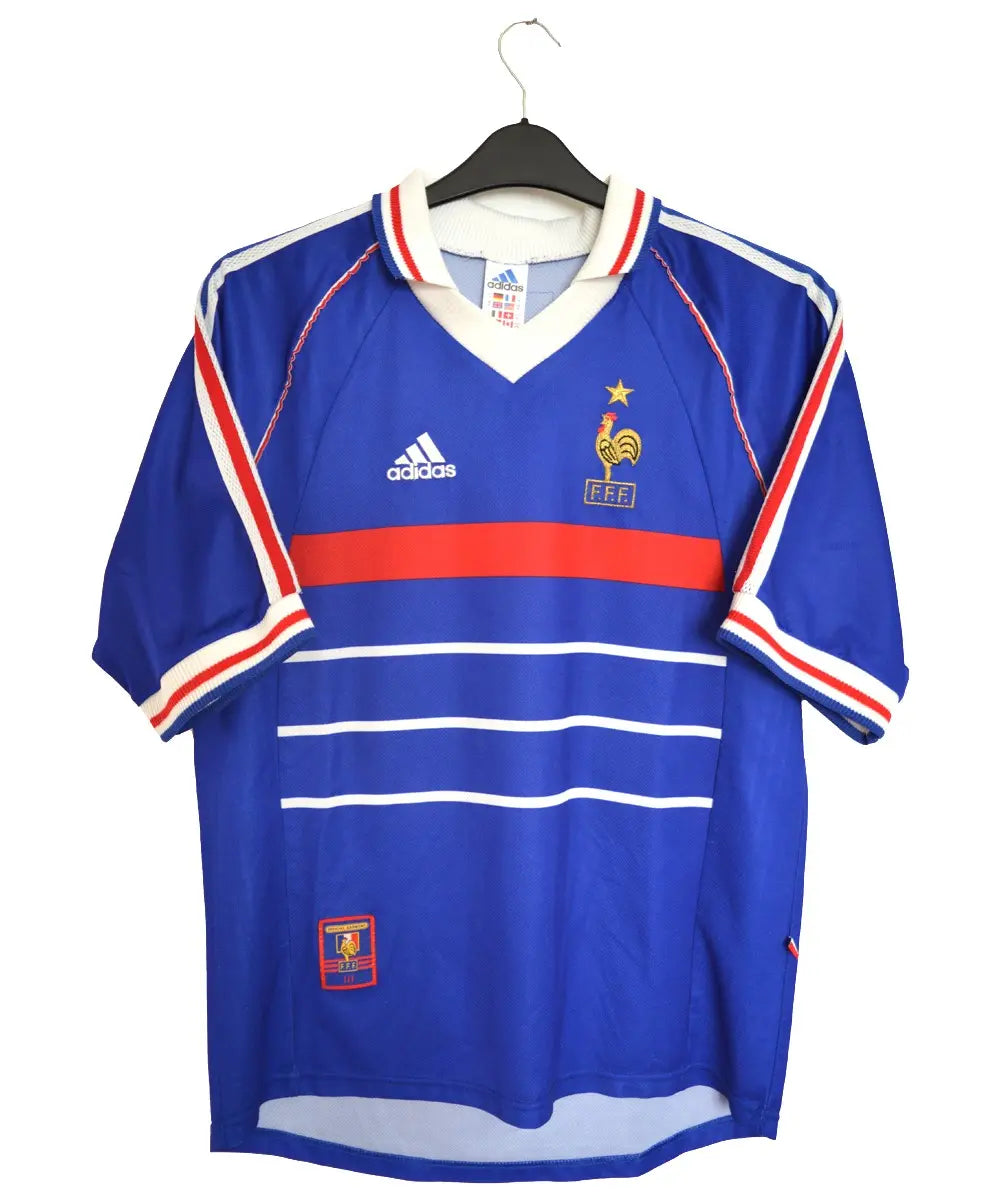 Maillot de foot retro/vintage authentique domicile de l'équipe de france 1998 floqué Zinedine Zidane. De couleur bleu et rouge, on peut retrouver l'équipementier adidas.