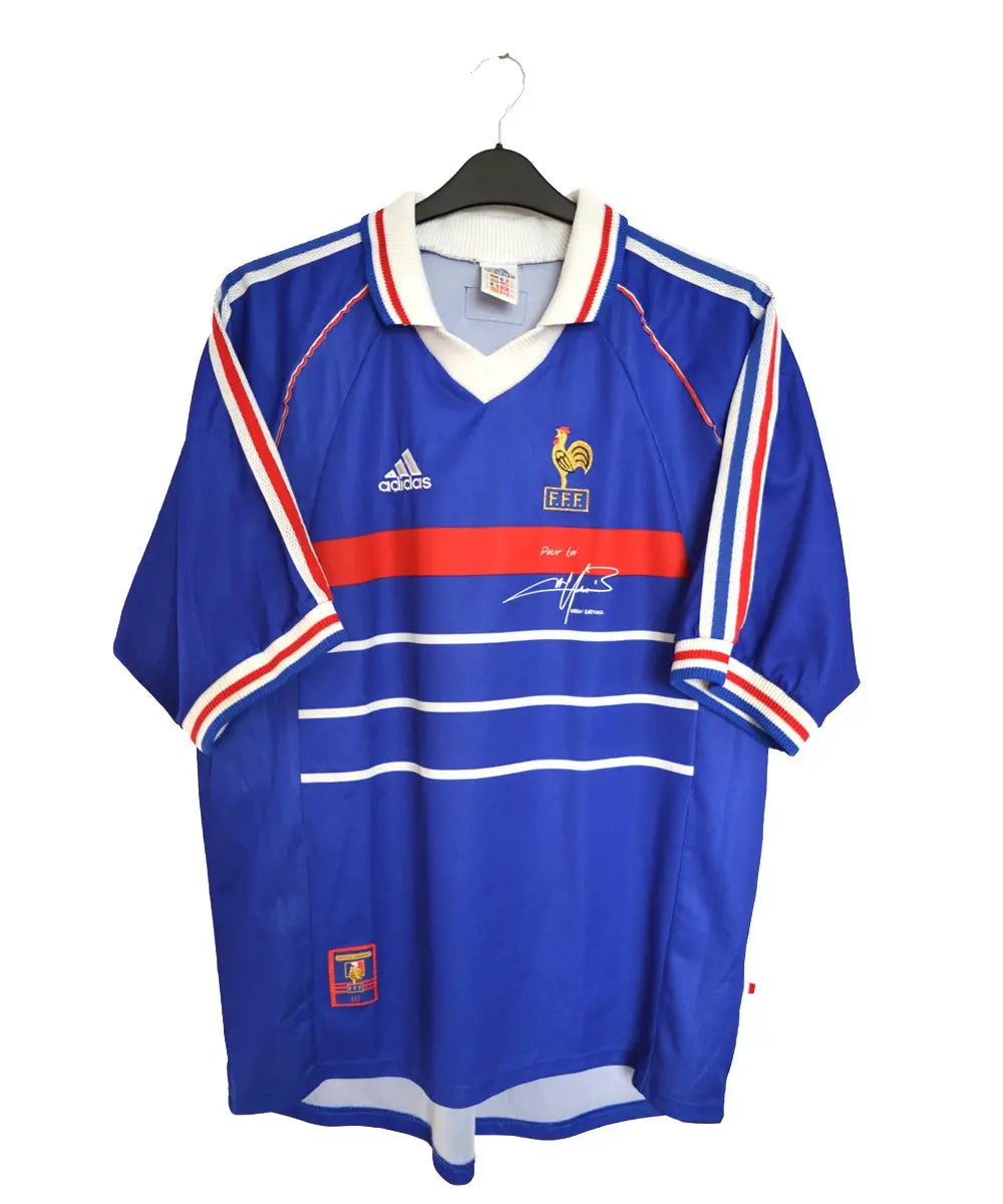 Maillot de foot retro/vintage authentique domicile de l'équipe de france 1998. De couleur bleu et rouge, on peut retrouver l'équipementier adidas ainsi qu'une signature de fabien barthez sur le maillot.